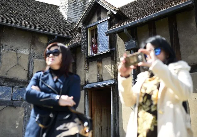 Tourists watch actors perform the Romeo and Juliet window scene at the house where William Shakespeare was born during celebrations to mark the 400th anniversary of the playwright's death in Stratford-Upon-Avon, Britain, April 23, 2016. (Photo by Dylan Martinez/Reuters)