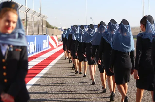Gulf air hostesses leave the track after a presentation of Formula One drivers' prior to the start of the Formula One Bahrain Grand Prix at Sakhir circuit in Manama on April 6, 2014. Mercedes driver Nico Rosberg of Germany took pole position for the Bahrain Grand Prix with teammate Lewis Hamilton ensuring a Mercedes lockout of the front row. (Photo by Marwan Naamani/AFP Photo)