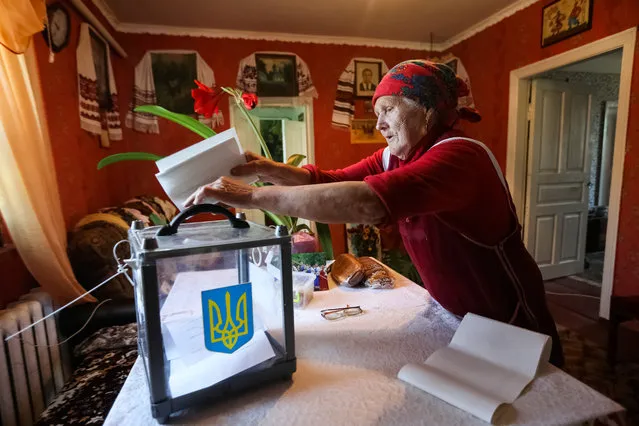 A local resident casts her vote into a mobile ballot box in a house during a parliamentary election in the village of Velyka Bugayivka in Kiev Region, Ukraine on July 21, 2019. (Photo by Konstantin Chernichkin/Reuters)