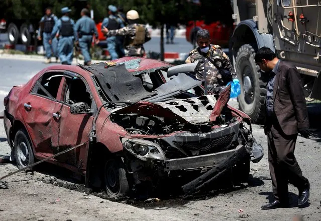 An Afghan security personnel inspects a damaged car at the site of a suicide bomb attack in Kabul, Afghanistan June 30, 2015. (Photo by Ahmad Masood/Reuters)