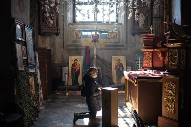 A woman prays at the cathedral during the funeral ceremony for Ukrainian officer Ivan Skrypnyk on March 17, 2022 in Lviv, Ukraine. The soldier died in Sunday's airstrike on the nearby International Center for Peacekeeping and Security at the Yavoriv military complex. The barrage of Russian missiles killed 35 and wounded scores. The site, west of Lviv in the town of Starychi, is mere miles from Ukraine's border with Poland. (Photo by Alexey Furman/Getty Images)