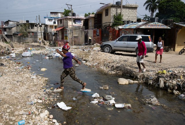 Residents cross a stream of water near a central street in Port-au-Prince, Haiti, 02 June 2024. The Haitian Prime Minister-designate, Garry Conille, arrived in the country on 01 June from abroad to assume office in a nation plunged into an unprecedented sociopolitical crisis. Last year, 8000 people fell victim to violence in Haiti, an insecurity that has further increased since the end of February. (Photo by Orlando Barría/EPA/EFE)