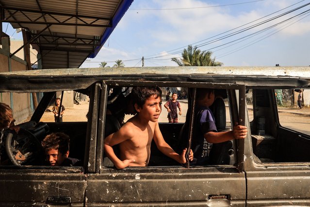 Internally displaced children play in a burnt out vehicle in the city of Deir al-Balah, in the central Gaza Strip on July 15, 2024, amid the ongoing conflict between Israel and the Palestinian Hamas militant group. (Photo by Eyad Baba/AFP Photo)