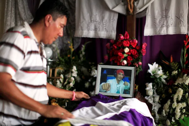 A man set a costume on the coffin of his brother Darwin Zelaya, DJ of a local radio killed by suspected gang members  in Izalco, El Salvador May 27, 2016. (Photo by Jose Cabezas/Reuters)