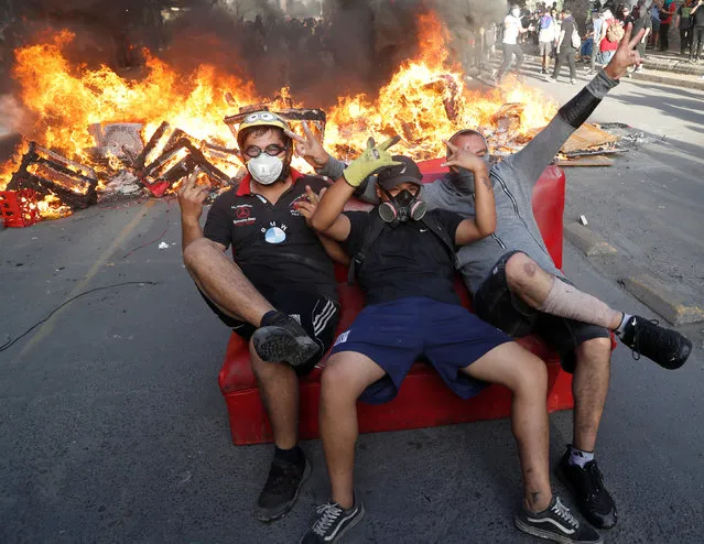 Demonstrators gesture in front of a burning barricade during a protest against Chile's government in Santiago, Chile on November 28, 2019. (Photo by Goran Tomasevic/Reuters)