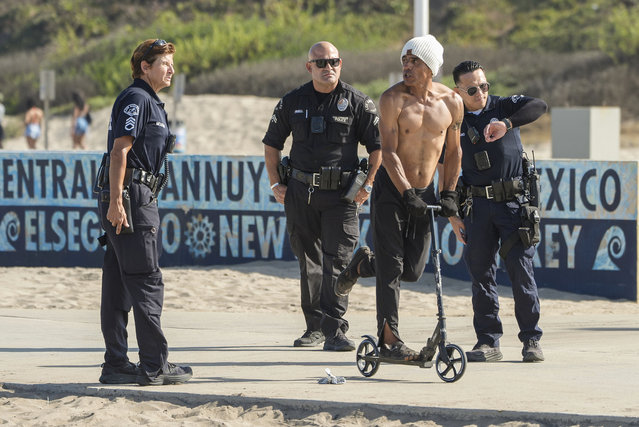 Rafael Rico rides away on a scooter as Los Angeles police and County Department of Beaches and Harbors workers remove his camp site during a cleanup operation to remove homeless encampments at the Dockweiler State Beach in Playa del Rey, Los Angeles, August 22, 2024. (Photo by Damian Dovarganes/AP Photo)