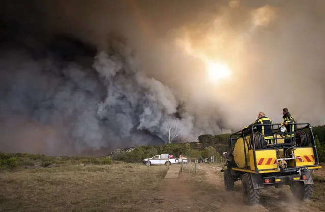 In this photo taken Wednesday, June 7, 2017, firemen fight a blaze in the Kranshoek area in South Africa. Fires fanned by high winds have swept through a scenic coastal town in South Africa, killing several people, destroying homes and forcing the evacuation of up to 10,000 people, authorities and media reports said Thursday. (Photo by Ewald Stander/AP Photo)