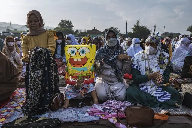 A girl holds a balloon as muslims women attend the Eid Al-Fitr prayer on the 'sea of sands' at Parangkusumo beach on May 02, 2022 in Yogyakarta, Indonesia. Muslims around the world celebrate Eid al-Fitr with their families with feasts to mark the end of Ramadan, the holy month of fasting. (Photo by Ulet Ifansasti/Getty Images)