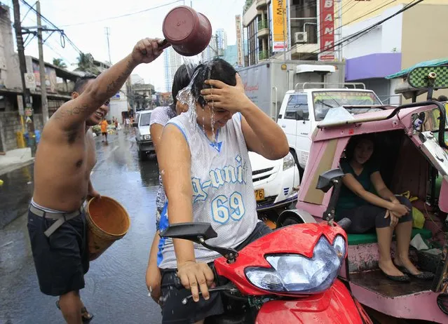 A resident douses motorists with water, during St. John the Baptist Feast Day celebrations in San Juan city, metro Manila June 24, 2014. Residents participate in an annual city-wide waterfest in honour of their patron Saint John the Baptist. (Photo by Romeo Ranoco/Reuters)
