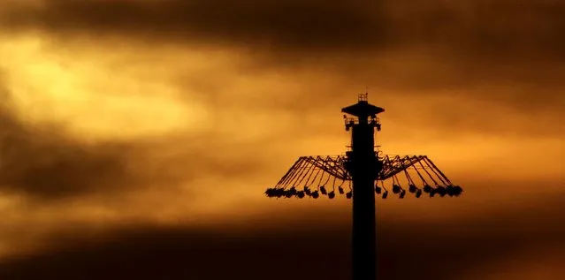 People riding an attraction are silhouetted as the sun sets beyond Worlds of Fun amusement park, Thursday, July 30, 2015, in Kansas City, Mo. (Photo by Charlie Riedel/AP Photo)