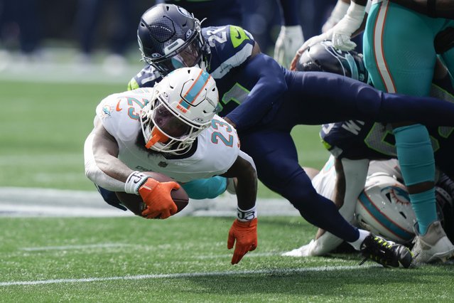 Miami Dolphins running back Jeff Wilson Jr. (23) drives as Seattle Seahawks cornerback Devon Witherspoon (21) defends during the first half of an NFL football game Sunday, September 22, 2024, in Seattle. (Photo by Stephen Brashear/AP Photo)