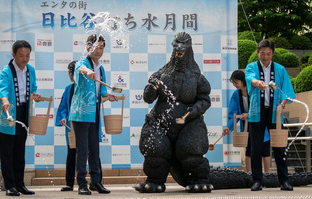 Godzilla (2nd R) and guests sprinkle water on the ground as part of an event to bring coolness to Tokyo's entertainment and business district of Hibiya on July 22, 2024. (Photo by Kazuhiro Nogi/AFP Photo)