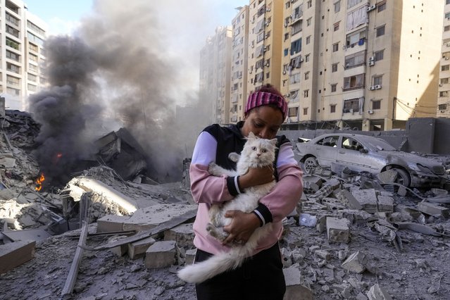 A woman holds her cat in front of a destroyed building at the site of an Israeli airstrike in Dahiyeh, Beirut, Lebanon, Wednesday, October 2, 2024. (Photo by Hassan Ammar/AP Photo)