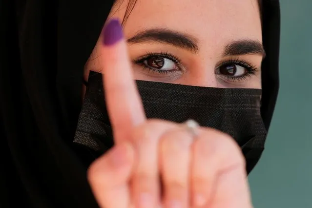 An Iraqi woman shows her ink-stained finger after casting her vote at a polling station during the parliamentary election, in Baghdad, Iraq on October 10, 2021. (Photo by Teba Sadiq/Reuters)