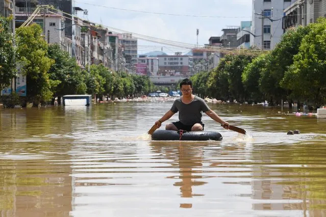 A man rows an inflatable ring in a flooded street after torrential rains on June 23, 2022 in Yingde, Qingyuan City, Guangdong Province of China. Flood control authority of China's Guangdong Province activated a Level-I emergency response on Tuesday. (Photo by Chen Chuhong/China News Service via Getty Images)