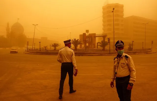 Traffic police officers direct vehicles during a sandstorm in Baghdad, Iraq on May 23, 2022. (Photo by Thaier Al-Sudani/Reuters)