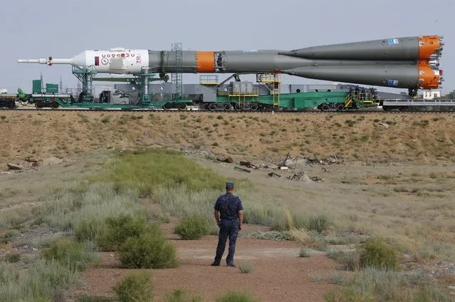 A policeman stands guard as Russia's Soyuz-FG booster rocket with the Soyuz MS space ship that will carry new crew to the International Space Station (ISS) is transported from its hangar to the launch pad at the Russian leased Baikonur cosmodrome, Kazakhstan, Monday, July 4, 2016. The start of the new Soyuz mission is scheduled on Thursday, July 7. The Russian rocket will carry U.S. astronaut Kate Rubins, Russian cosmonaut Anatoly Ivanishin and Japanese astronaut Takuya Onishi. (Photo by Dmitri Lovetsky/AP Photo)