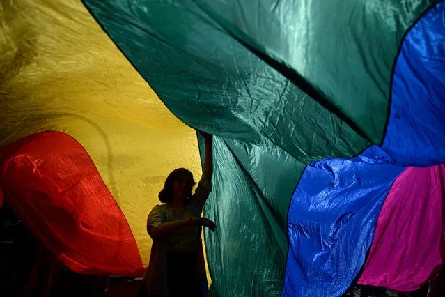 A woman is seen under a giant flag during the annual Gay Pride parade also known as “La Marche des Fiertes LGBT+” in French in Strasbourg, eastern France, on June 18, 2022. (Photo by Sebastien Bozon/AFP Photo)