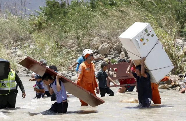 People carry their belongings while crossing the Tachira river border with Venezuela into Colombia, near Villa del Rosario village August 25, 2015. (Photo by Jose Miguel Gomez/Reuters)