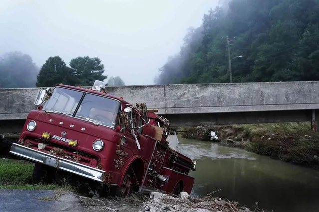 A fire truck is seen hangin over the edge of the water propped against a bridge on Wednesday, August 3, 2022, in Hindman, Ky., after massive flooding carried the fire truck towards the water.  Temperatures are soaring in a region of eastern Kentucky where people are shoveling out the wreckage of massive flooding. (Photo by Brynn Anderson/AP Photo)
