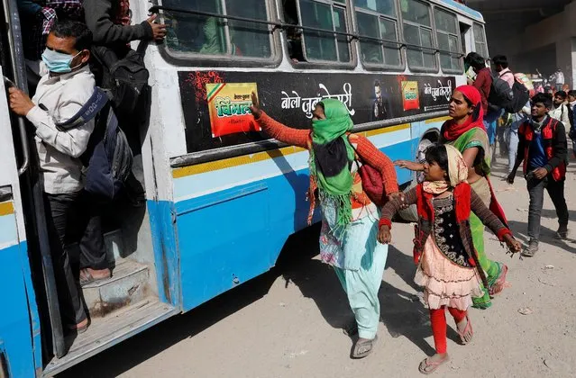 A migrant worker holds her daughter's hand as she tries to board a crowded bus to return to her village in Ghaziabad, on the outskirts of New Delhi, India, March 29, 2020. (Photo by Adnan Abidi/Reuters)