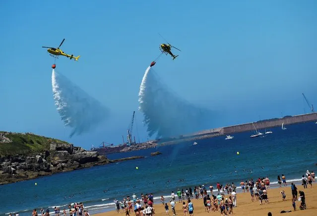 Two helicopters of the Asturias Fire Service fly over San Lorenzo beach during an aerial exhibition in Gijon, northern Spain, northern Spain, July 24, 2016. (Photo by Eloy Alonso/Reuters)