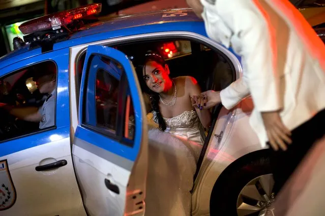 A girl from the Santa Marta favela exits a police car, taking the hand of an officer who patrols her neighborhood as she arrives for the debutante ball organized by her slum's Pacifying Police Unit. (Photo by Silvia Izquierdo/AP Photo via The Palm Beach Post)