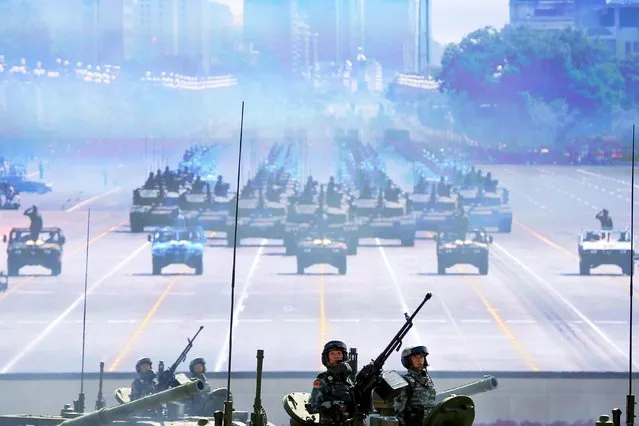 Soldiers of the People's Liberation Army (PLA) of China roll on their armoured vehicles to Tiananmen Square as others are shown on a big screen during the military parade marking the 70th anniversary of the end of World War Two, in Beijing, China, September 3, 2015. (Photo by Damir Sagolj/Reuters)