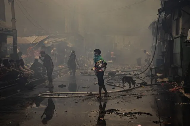 Residents retrieve their things as a fire engulfs their houses in a slum community on April 15, 2020 in Manila, Philippines. According to authorities, more than a hundred residents were rendered homeless after a fire razed the slum community, amid a government lockdown which has made the country's homeless vulnerable and in need of aid. Close to 70 percent of the homeless population are in Metro Manila and survive by begging, or collecting and reselling plastic and metal scraps. The Philippines' main island Luzon, which includes the capital Manila, remains on lockdown as authorities continue to struggle with the growing number of coronavirus, Covid-19 cases. Land, sea, and air travel has been suspended, while government work, schools, businesses, and public transportation have been ordered shut in a bid to keep some 55 million people at home. The Philippines' Department of Health has so far confirmed 5,223 cases of the coronavirus in the country, with at least 335 recorded fatalities. (Photo by Ezra Acayan/Getty Images)