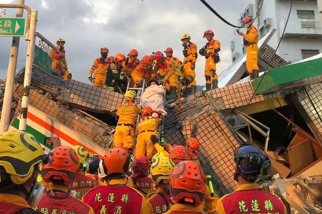 This handout photo taken and released on September 18, 2022 by the Taitung County Fire Bureau shows firefighters moving a person during a rescue operation at the site of a collapsed building after a magnitude 6.9 earthquake, in Yuli township, Hualien County. - A strong earthquake struck southeastern Taiwan on September 18, bringing at least three buildings down in a small town and tearing up roads – but forecasters said the threat of a regional tsunami had passed. (Photo by Handout/Taitung County Fire Bureau/AFP Photo)