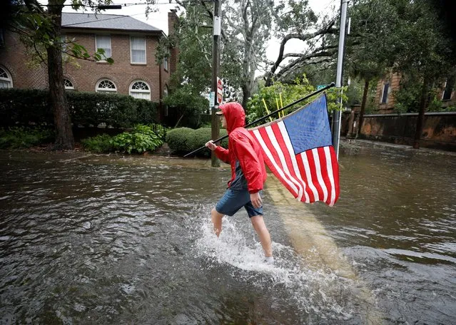 Caden Simmons, a 16-year-old local resident, walks with a U.S. flag on a flooded street after he recovered it from flood waters, as Hurricane Ian bears down on Charleston, South Carolina, U.S., September 30, 2022. (Photo by Jonathan Drake/Reuters)
