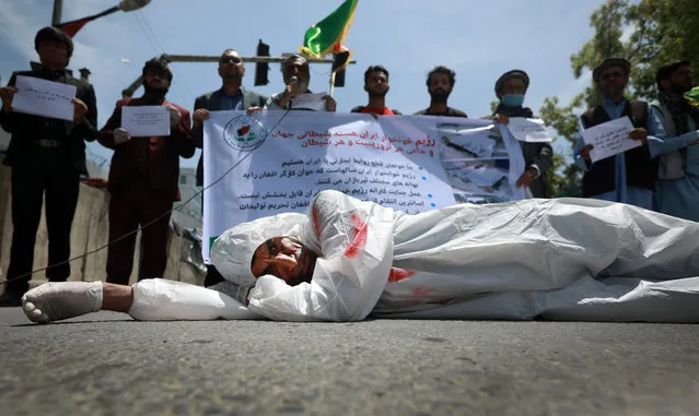 An Afghan man wearing clothes spattered in blood lays down on a road as protesters shout slogans against the Iranian regime and demand justice during a protest outside the Iranian Embassy in Kabul, Afghanistan, 07 May 2020. Dozens of Afghan migrants returned from Iran claim that Iran border guards tortured and killed at least 23 Afghan workers by throwing them into a river on 02 May 2020. (Photo by Jawad Jalali/EPA/EFE)