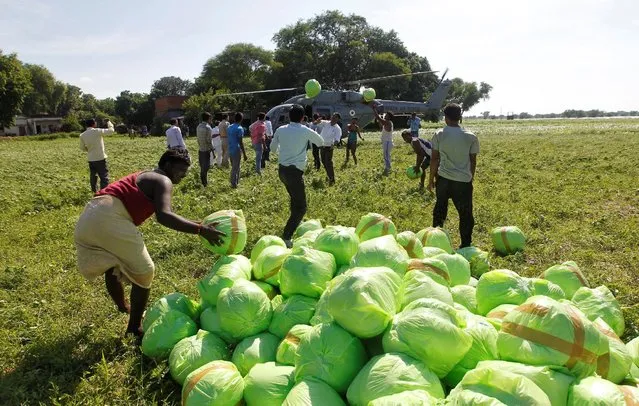 People unload relief food material from an Indian Air Force helicopter to be distributed among the flood victims, on the outskirts of Allahabad, India, August 24, 2016. (Photo by Jitendra Prakash/Reuters)