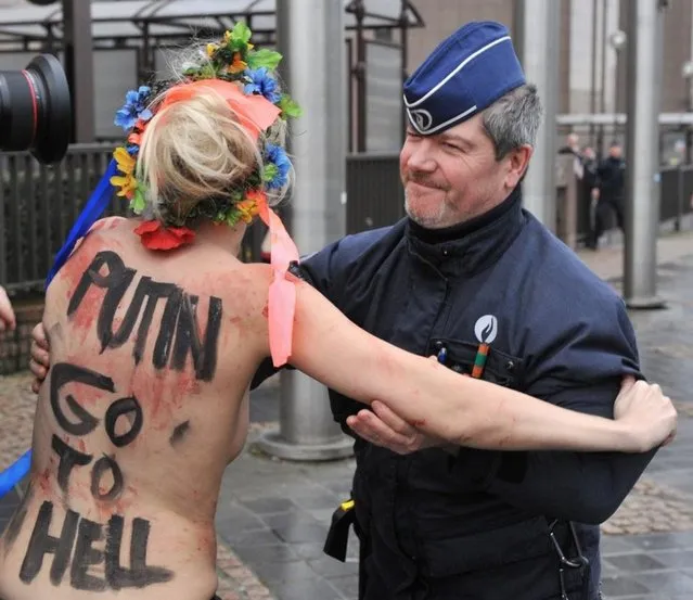 An activist of Ukraine's feminist movement Femen is taken away by the police as she demonstrates by the EU Council building where the EU-Russia summit is taking on December 21, 2012 in Brussels, Belgium. (Photo by Georges Gobet/AFP Photo)