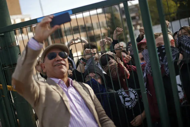 A man takes a selfie with protesting students standing behind a barricade blocking the entrance to Madrid's Complutense University on the second day of a nationwide student strike against rising fees and educational cuts, October 22, 2014. (Photo by Susana Vera/Reuters)