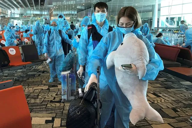 A Vietnamese woman carries a stuffed animal while boarding a repatriation flight from Singapore to Vietnam amid spread of the coronavirus disease (COVID-19) outbreak at Changi airport, Singapore on August 7, 2020. (Photo by Mai Nguyen/Reuters)