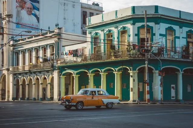 A mustard coloured vintage car drives down Central Havana's streets, Cuba, July 2016. (Photo by Bobi Dojcinovski/REX Shutterstock)