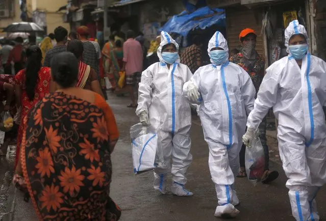 Health workers return after screening people for COVID-19 symptoms in Dharavi, one of Asia's biggest slums, in Mumbai, India, Tuesday, August 11, 2020. India has the third-highest coronavirus caseload in the world after the United States and Brazil. (Photo by Rafiq Maqbool/AP Photo)