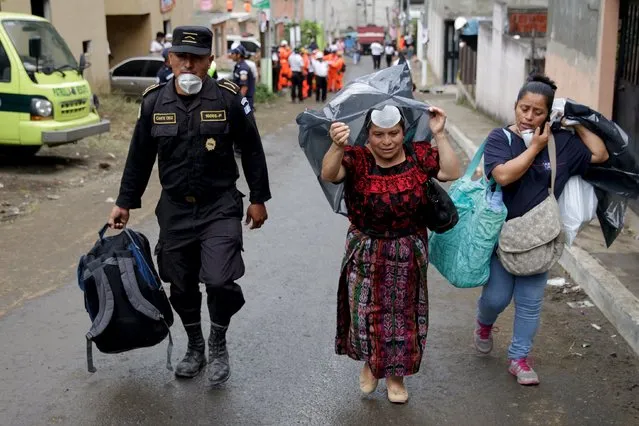 A policeman escorts two women, who are looking for missing relatives, away from an area affected by a mudslide, in Santa Catarina Pinula, on the outskirts of Guatemala City, October 4, 2015. Guatemalan authorities on Sunday said that around 300 people remain missing after a massive landslide on Thursday night claimed at least 87 lives and flattened over a hundred homes. (Photo by Josue Decavele/Reuters)