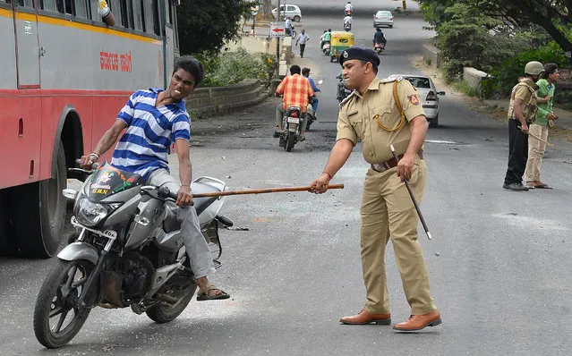 A police personnel canes a motorcyclist during a curfew following violence in the city due to the Cauvery water sharing dispute with neighbouring state Tamil Nadu, in Bangalore on September 13, 2016. Prime Minister Narendra Modi appealed for calm September 13, in the Indian tech hub of Bangalore which has been placed under curfew after deadly violence erupted over a long-running dispute with a neighbouring state over access to water. (Photo by Manjunath Kiran/AFP Photo)