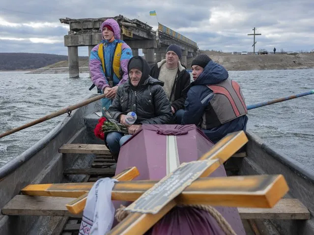 A woman sits in a boat crossing the Siverskyi-Donets river near Staryi-Saltiv, Kharkiv region on Wednesday January 4, 2023, transporting the coffin containing her dead son, a soldier who was killed in fighting with Russians. (Photo by Erik Marmor/AP Photo)