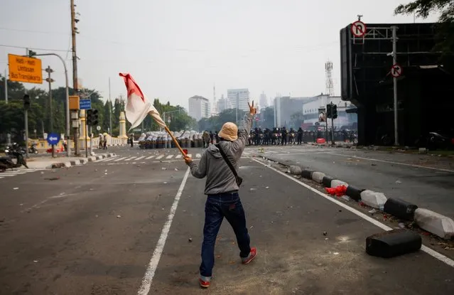 A demonstrator holds an Indonesian flag as he gestures in front of police officers during a protest against the government's labour reforms in a controversial jobs creation law in Jakarta, Indonesia, October 8, 2020. (Photo by Willy Kurniawan/Reuters)