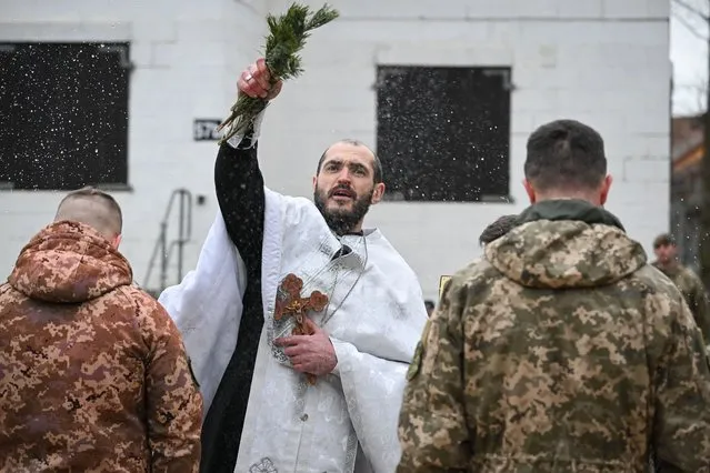 A Ukrainian Orthodox Priest blesses the Ukrainian soldiers at the end of the service, on February 23, 2023 near Salisbury, England. Ahead of tomorrow's anniversary of the Russian Invasion of Ukraine, hundreds of soldiers from the Armed Forces of Ukraine and their UK instructors come together to remember those who have lost their lives in the war on Ukraine. (Photo by Finnbarr Webster/Getty Images)