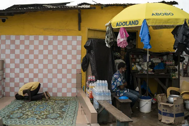 A Muslim prays next to a kiosk with a parasol reading “Abobo ADOland” in reference to the Ivory Coast President Alassane Ouattara, who is known as ADO, at Abobo neighborhood, in Abidjan, Ivory Coast, Monday, November 2, 2020. International election observers in Ivory Coast said Monday that voter turnout was “extremely low” in parts of the country after leading opposition candidates called for a boycott to protest President Alassane Ouattara's bid for a controversial third term. (Photo by Leo Correa/AP Photo)