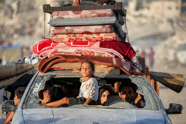 A girl rides through the broken windshield at the front of a vehicle transporting people and their belongings while evacuating southbound from Gaza City on September 2, 2025. Israel intensified its military build-up on September 2 as reservists began responding to call-up orders ahead of a planned offensive on Gaza City, despite mounting pressure at home and abroad to end the nearly two-year campaign in the Palestinian territory. (Photo by Eyad Baba/AFP Photo)