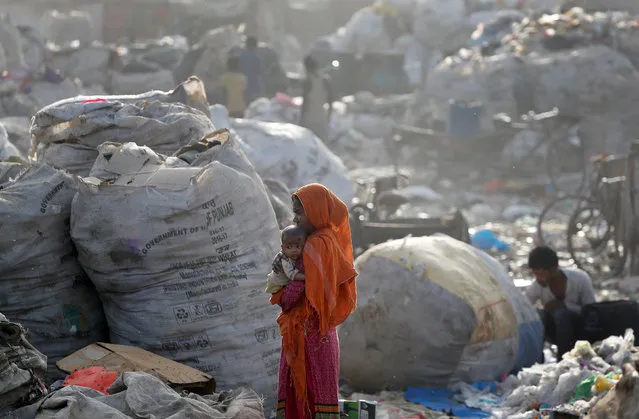 A woman carries her baby through a rubbish dump in Delhi, India, March 27, 2018. (Photo by Cathal McNaughton/Reuters)
