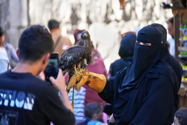 A Syrian boy, left, takes picture by a mobile phone for a veiled woman holds a hawk in the old city of Damascus, Syria, Thursday, October 2, 2025. (Photo by Hussein Malla/AP Photo)