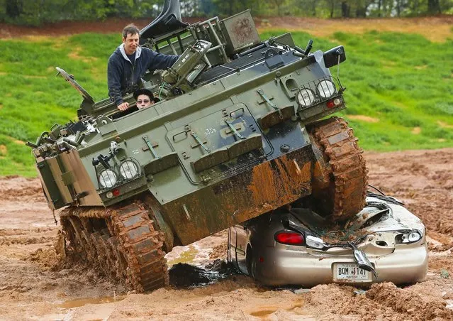 Brunner Waterman, 15, crushes a Ford Taurus with owner Todd Liebross, supervising at Tank Town USA, a heavy equipment playground where you can drive tanks and crush cars in Morganton, Ga., on April 28, 2013. The experience was a surprise gift from his parents Eric & Heather Waterman who brought their two sons and a friend from Laurens, S.C., to make a life long memory. (Photo by Curtis Compton/AJC)