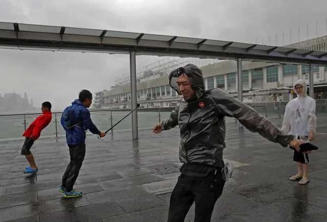 People play with strong wind caused by Typhoon Haima on the waterfront of Victoria Habour in Hong Kong, Friday, October 21, 2016. (Photo by Vincent Yu/AP Photo)