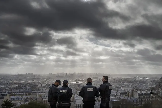 French Police officers stand on guard near the church of Sacre Coeur, on top of the Montmartre hill with Paris, Wednesday, November 18, 2015. A woman wearing an explosive suicide vest blew herself up Wednesday as heavily armed police tried to storm a suburban Paris apartment where the suspected mastermind of last week's attacks was believed to be holed up, police said. (Photo by Daniel Ochoa de Olza/AP Photo)